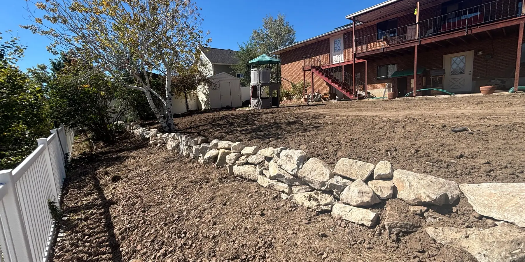 Backyard being graded with a new rock retaining wall