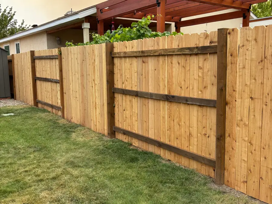 Cedar fence boards in evening light with a pergola behind