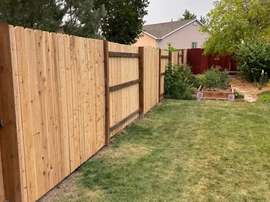 Cedar privacy fence beside a lawn and garden beds