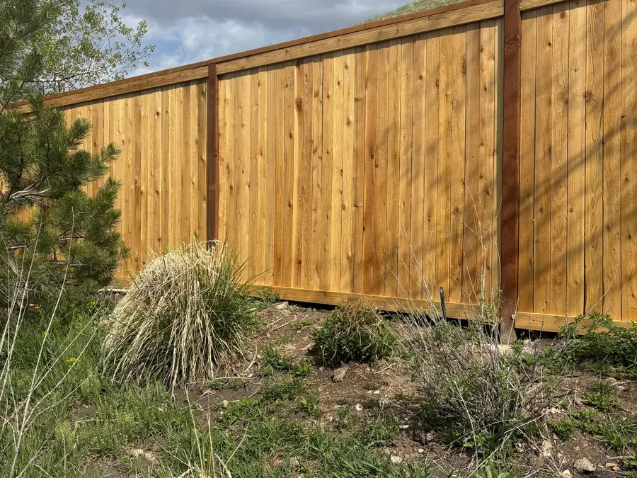 Cedar privacy fence on a hillside lot under a cloudy sky
