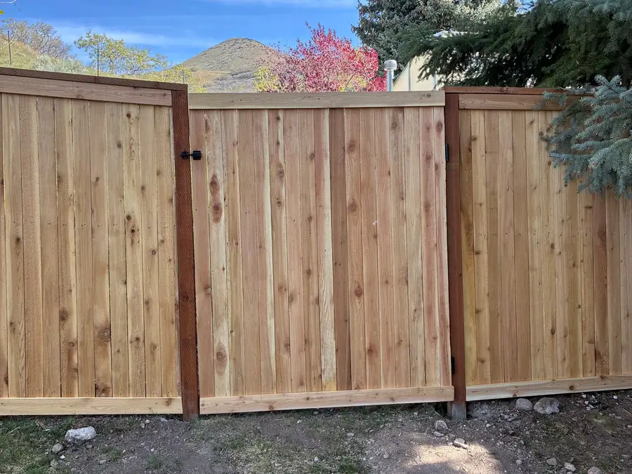 New cedar fence and gate with a flowering tree and mountains behind