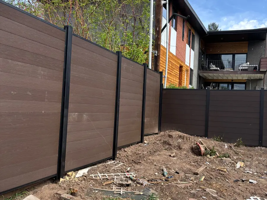 Corner of a composite privacy fence with a modern home behind