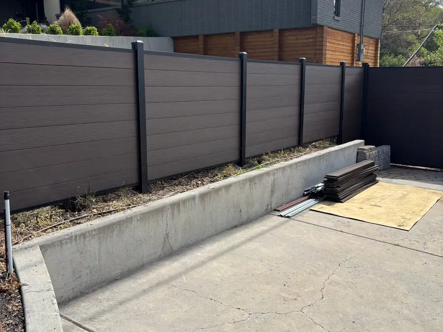 Composite fence beside a concrete driveway and a modern home
