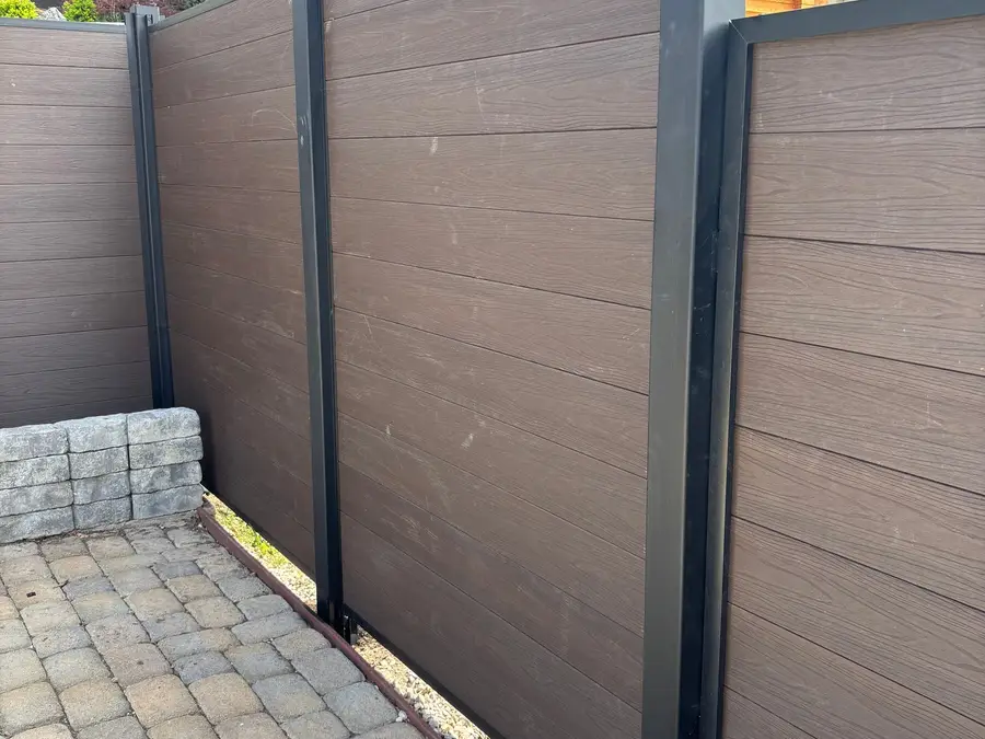 Composite fence beside a paver walkway and retaining wall