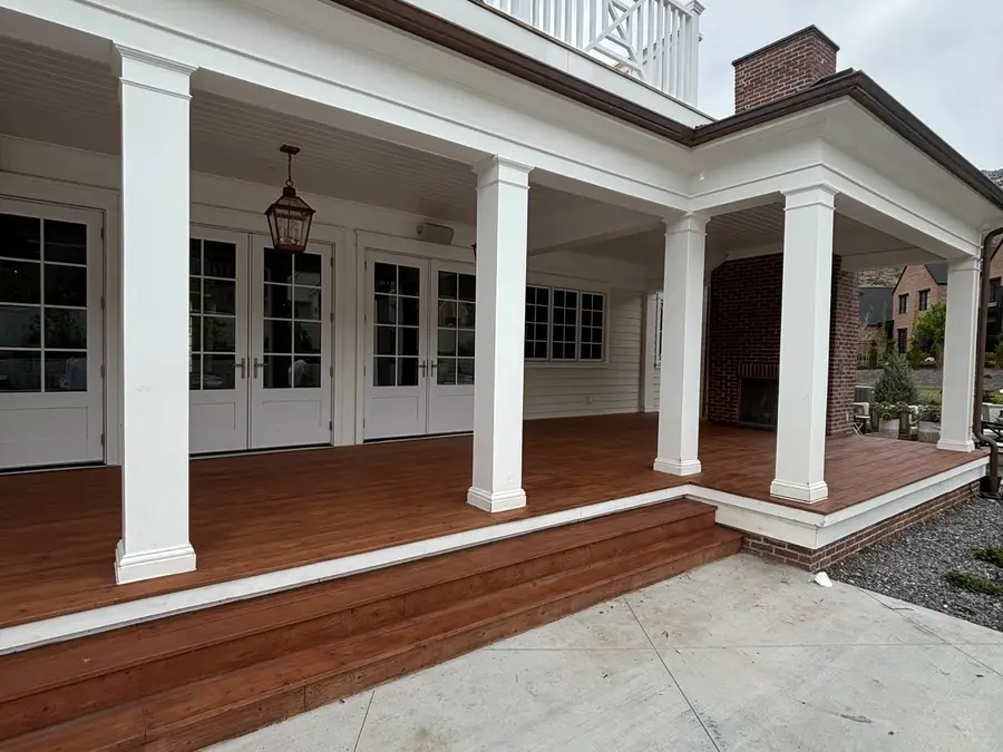 Covered back porch with white columns, a hanging lantern, and a stained wood deck