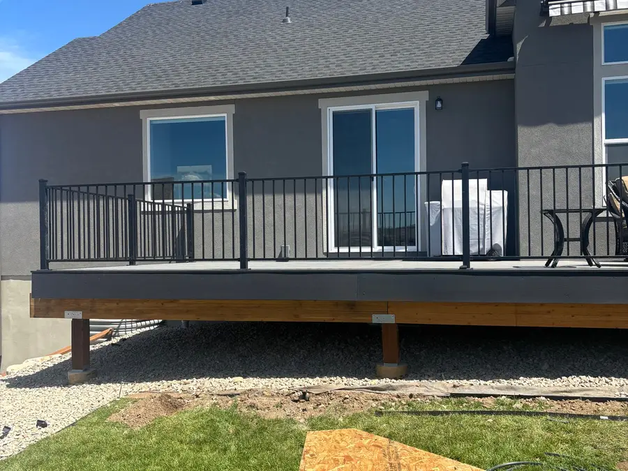 New deck with black metal railing on the back of a home