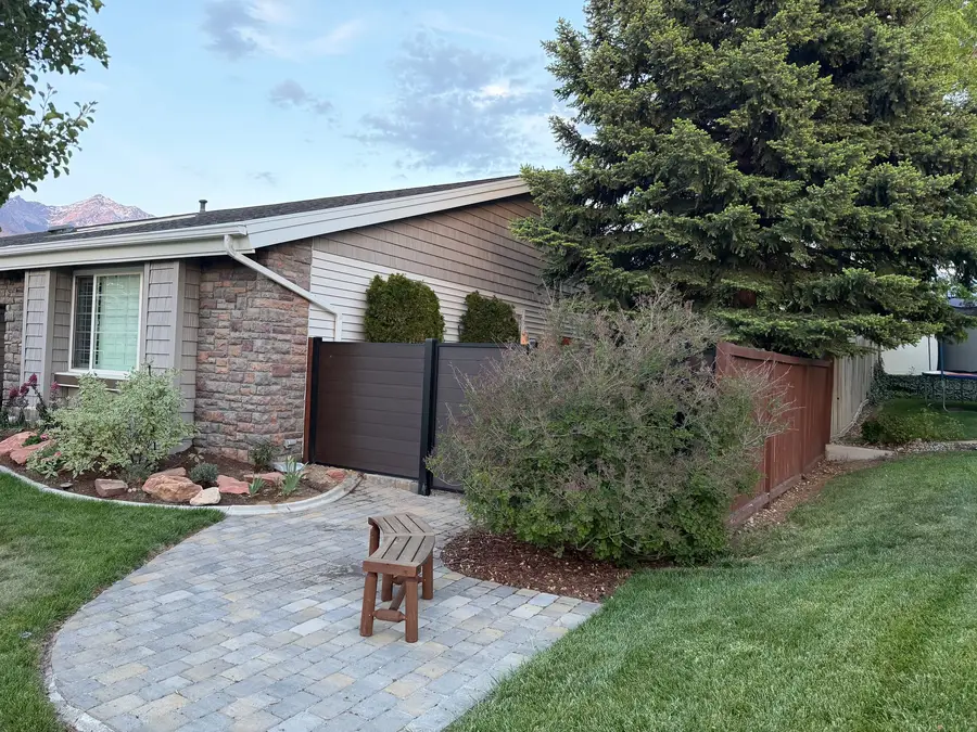 Composite fence, bench, and paver walkway along the side of a home