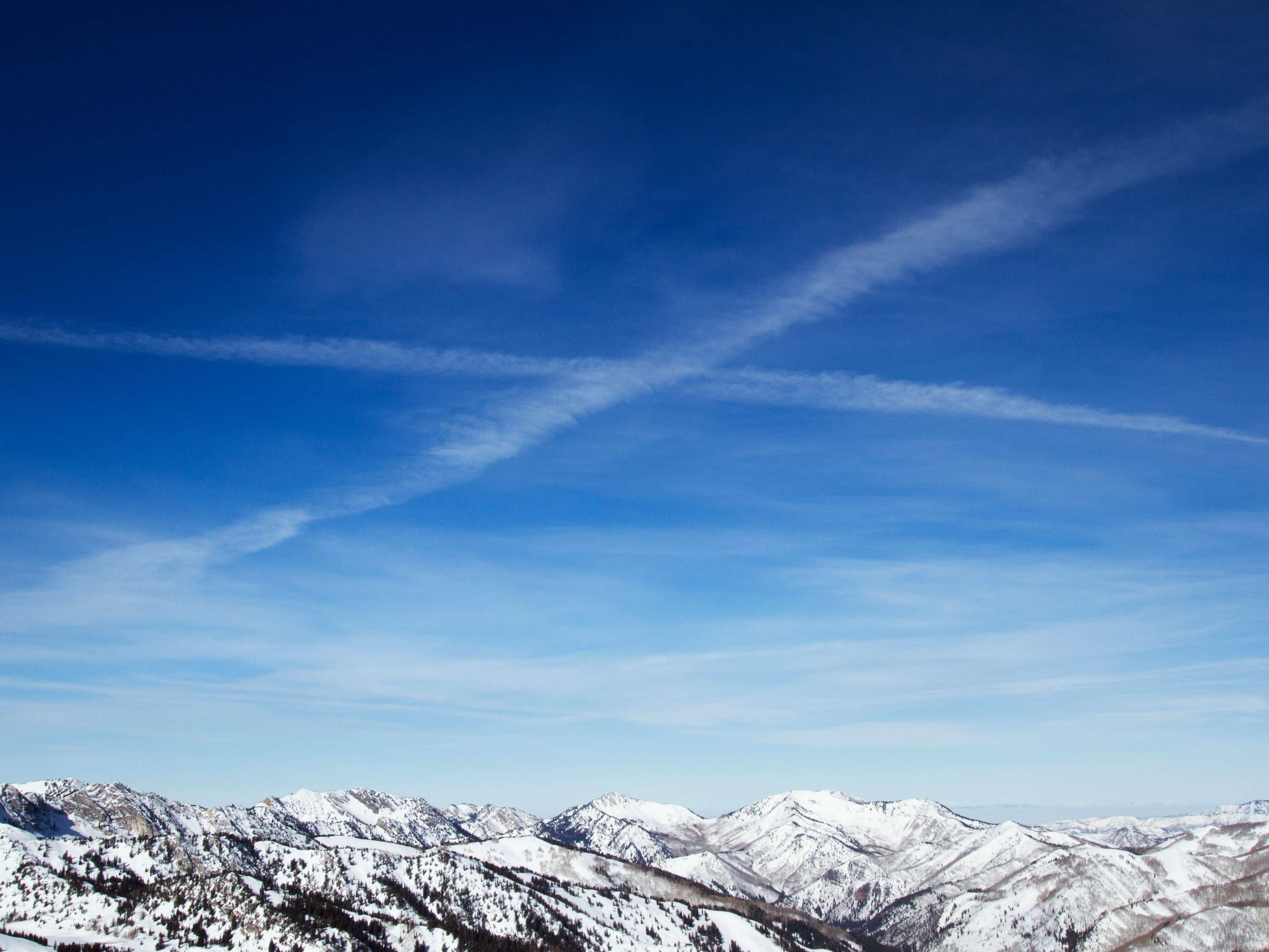 Snow-covered peaks of the Wasatch Range under a deep blue sky