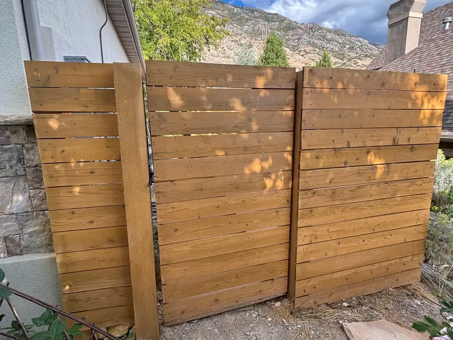 Horizontal cedar fence gate beside a stone wall