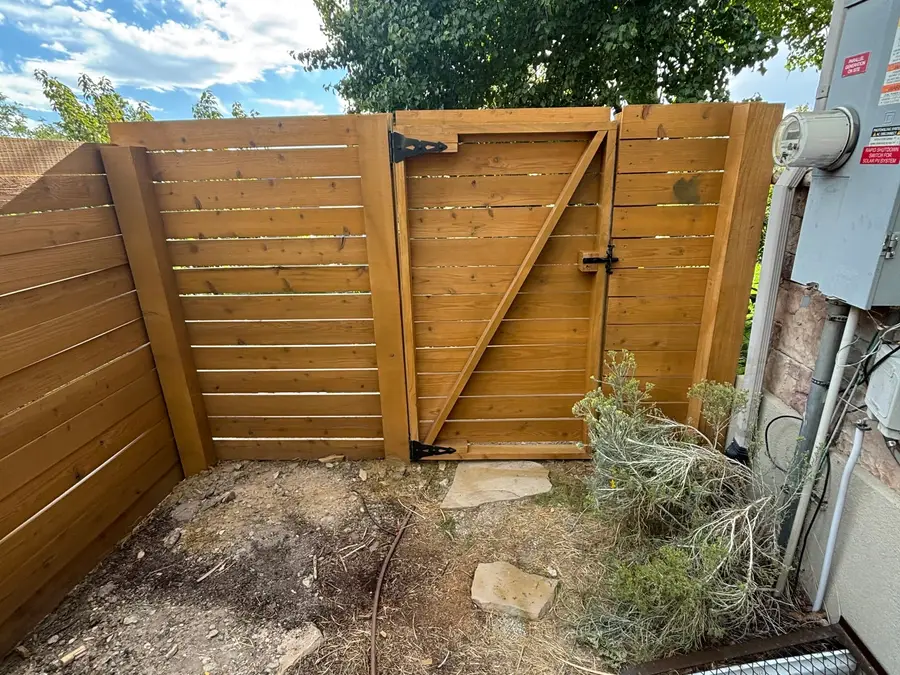 Horizontal cedar fence and gate beside a utility area