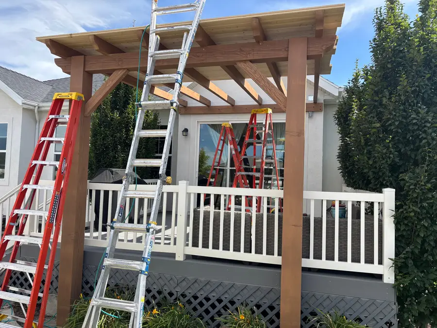 Pergola being built over a deck, with ladders in place