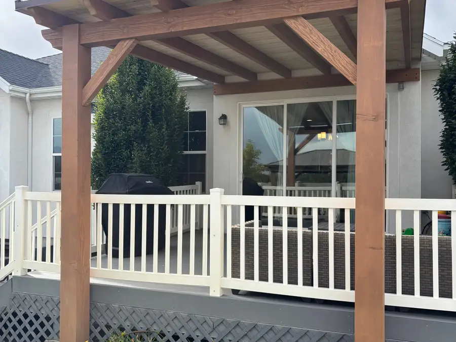 Cedar pergola over a deck with white railing at the back of a home